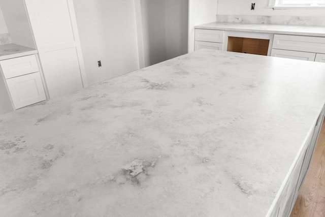 kitchen with white cabinets, built in desk, and light stone countertops