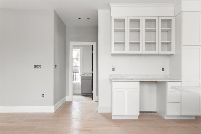 kitchen with light countertops, light wood-style flooring, glass insert cabinets, and white cabinetry