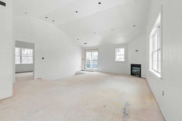 unfurnished living room featuring vaulted ceiling and a glass covered fireplace