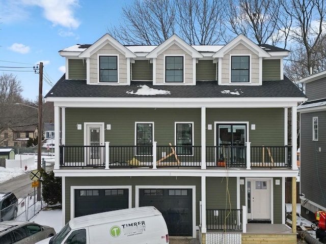 view of front facade featuring covered porch, roof with shingles, and an attached garage