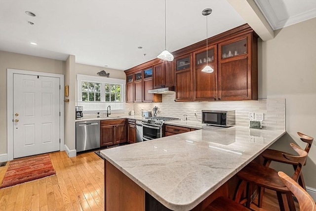49 Intrepid Cir Unit 49, Marblehead, MA 01945 - kitchen featuring stainless steel appliances, a peninsula, under cabinet range hood, a breakfast bar area, and tasteful backsplash