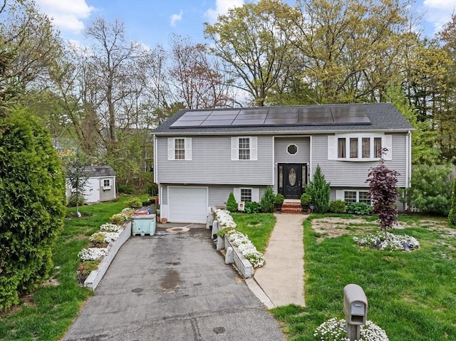 64 Ventura Ln, New Bedford, MA 02745 - split foyer home featuring asphalt driveway, solar panels, a shed, and a garage
