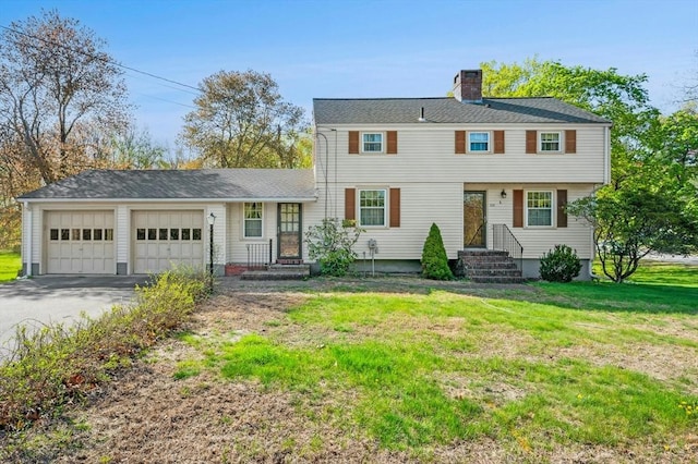 colonial inspired home with a garage, a chimney, driveway, and a front lawn