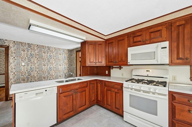 kitchen with brown cabinets, a sink, light countertops, wallpapered walls, and white appliances