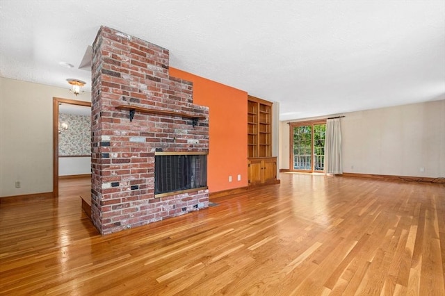 unfurnished living room featuring built in features, baseboards, a fireplace, and wood finished floors