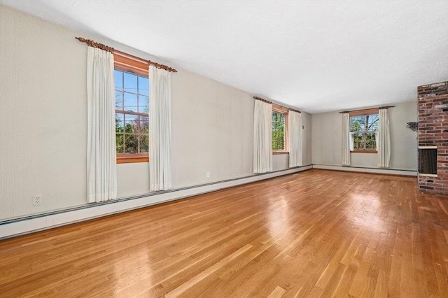 unfurnished living room featuring plenty of natural light, a fireplace, and wood finished floors