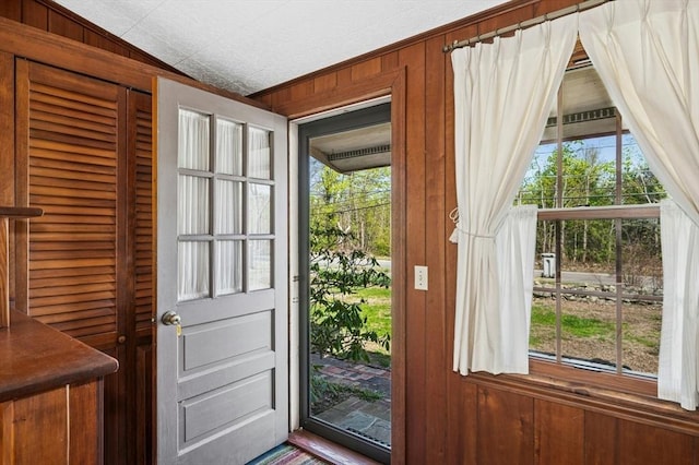 doorway to outside featuring wood walls and lofted ceiling