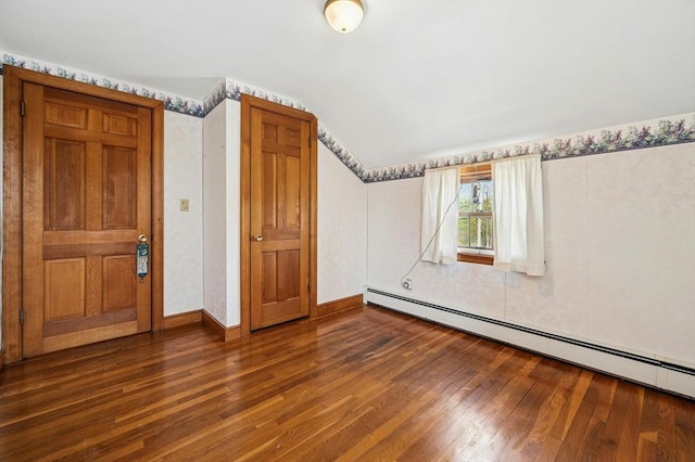 additional living space featuring baseboards, vaulted ceiling, baseboard heating, and wood finished floors
