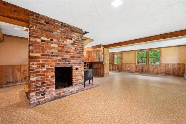 unfurnished living room featuring a textured ceiling, wood walls, and a wainscoted wall