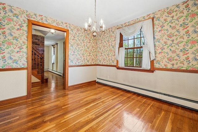 unfurnished room with wallpapered walls, an inviting chandelier, wainscoting, and light wood-style flooring