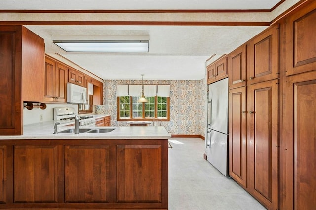 kitchen featuring brown cabinetry, a peninsula, white appliances, wallpapered walls, and light countertops