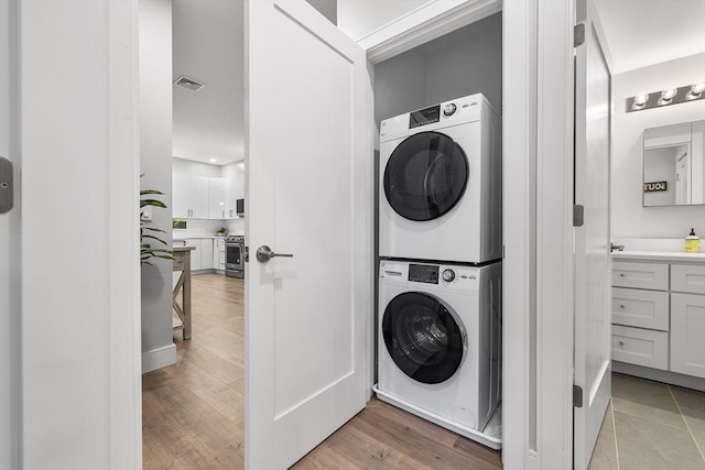 clothes washing area featuring stacked washer / drying machine and light hardwood / wood-style flooring