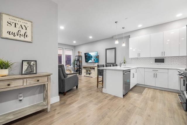 kitchen featuring white cabinetry, a kitchen bar, hanging light fixtures, stainless steel dishwasher, and kitchen peninsula