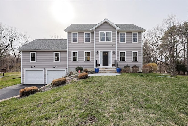 colonial house with driveway, an attached garage, a front lawn, and roof with shingles
