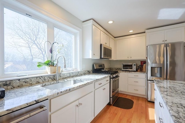 585 Chestnut St, Ashland, MA 01721 - kitchen with light wood-style flooring, a toaster, stainless steel appliances, white cabinetry, and a sink