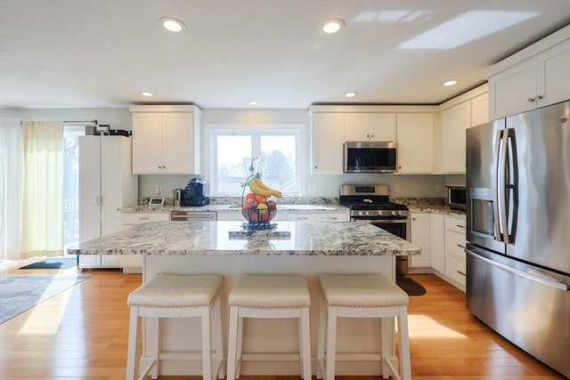 585 Chestnut St, Ashland, MA 01721 - kitchen with white cabinetry, stainless steel appliances, a breakfast bar area, and light wood-type flooring