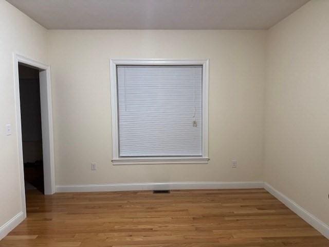 spare room featuring light wood-style floors, visible vents, and baseboards