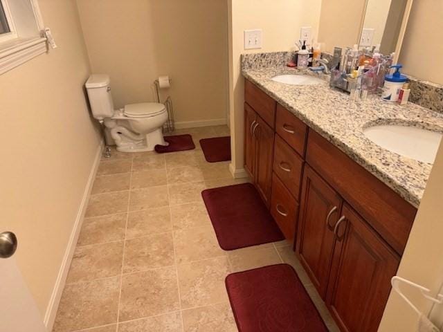 full bath with double vanity, a sink, toilet, and baseboards