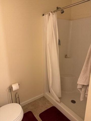 full bath with toilet, a shower stall, baseboards, and tile patterned flooring