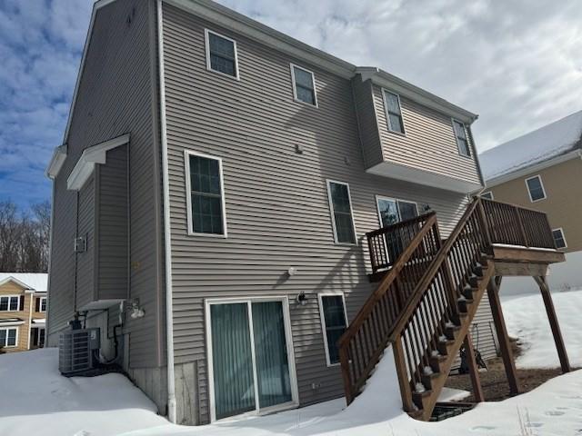 snow covered back of property featuring stairs, central AC, and a deck