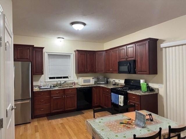 kitchen featuring a sink, light wood-style flooring, and black appliances