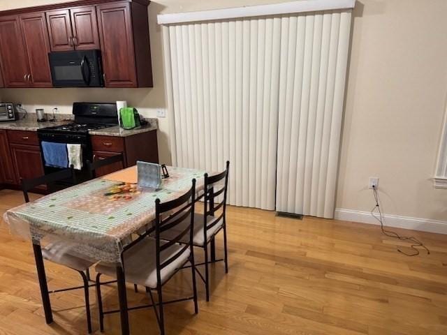 kitchen featuring black appliances, light wood finished floors, visible vents, and baseboards