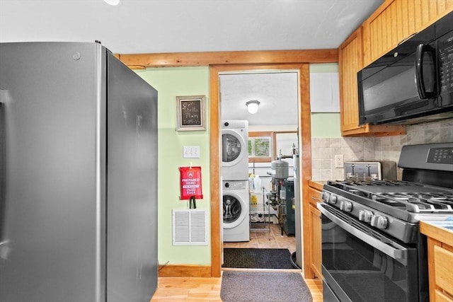 13 Elcott Rd, Quincy, MA 02169 - kitchen featuring appliances with stainless steel finishes, stacked washer / drying machine, tasteful backsplash, and light wood-style floors