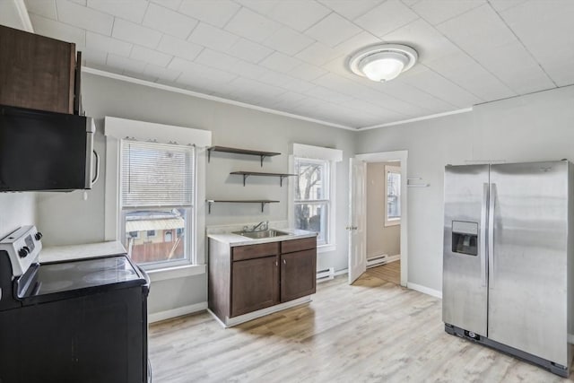 kitchen with light countertops, appliances with stainless steel finishes, light wood-style floors, a sink, and washer / dryer