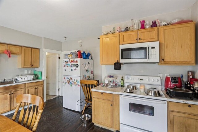 kitchen featuring light countertops, white appliances, dark wood-type flooring, and a sink