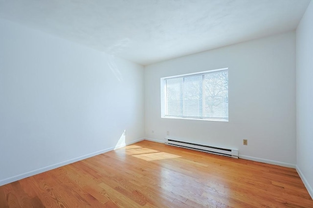 spare room featuring baseboards, light wood-type flooring, and a baseboard radiator