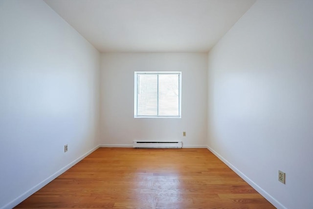 spare room with baseboard heating, baseboards, and light wood-style floors