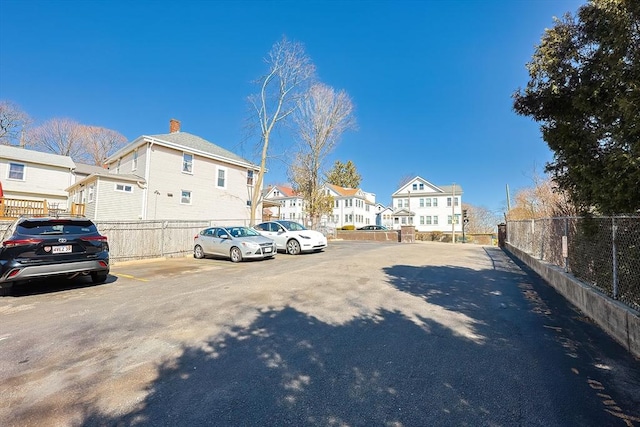 uncovered parking lot featuring a residential view and fence