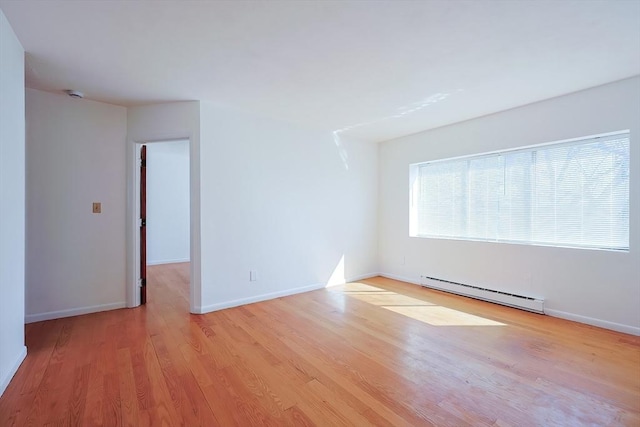 empty room featuring a baseboard heating unit, baseboards, and wood finished floors