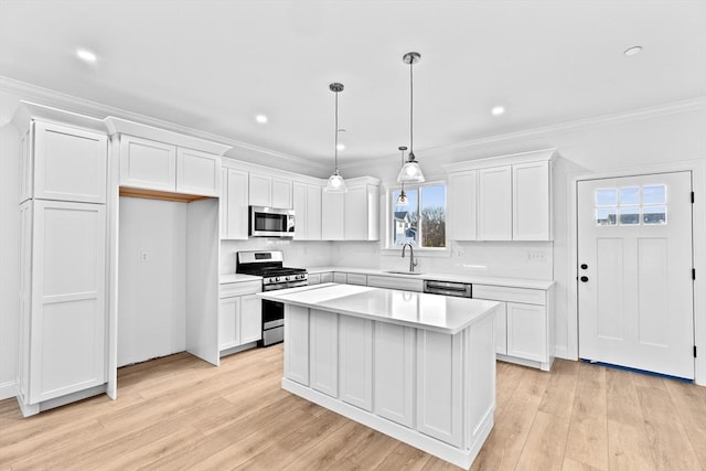 kitchen with a sink, a kitchen island, white cabinetry, appliances with stainless steel finishes, and light countertops