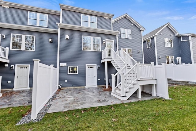 rear view of house with stairway, a patio area, fence, and a lawn