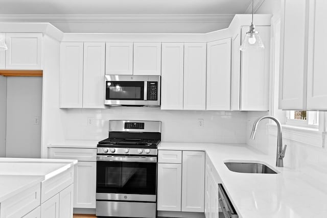 kitchen with ornamental molding, white cabinetry, stainless steel appliances, and a sink