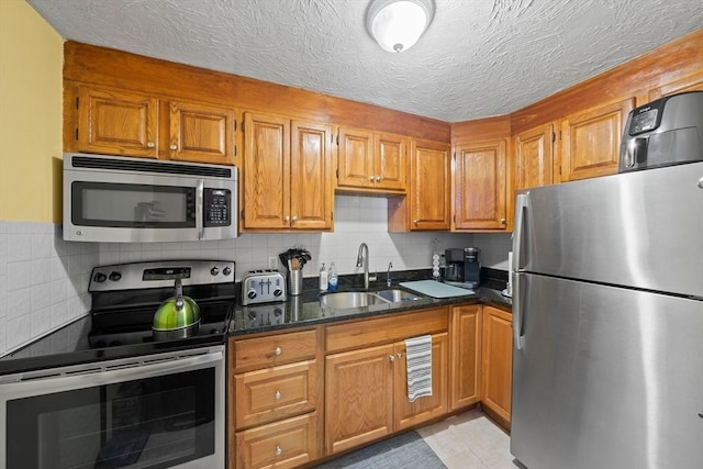 79 Fountain Unit 5, Weymouth, MA 02190 - kitchen featuring brown cabinets, appliances with stainless steel finishes, a sink, dark stone countertops, and backsplash
