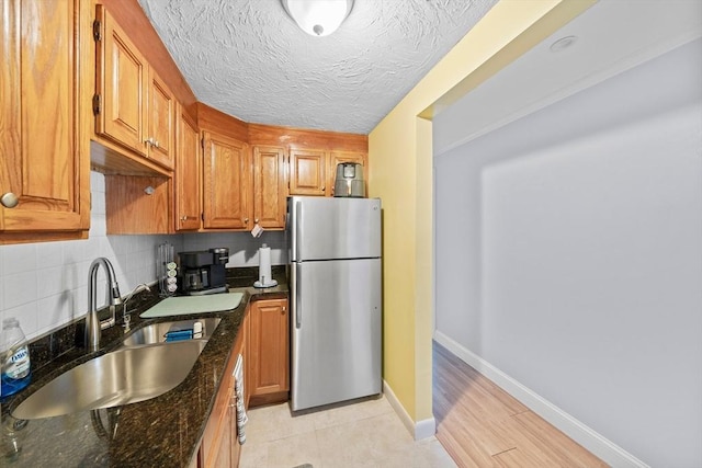 79 Fountain Unit 5, Weymouth, MA 02190 - kitchen with decorative backsplash, brown cabinetry, a sink, freestanding refrigerator, and dark stone counters