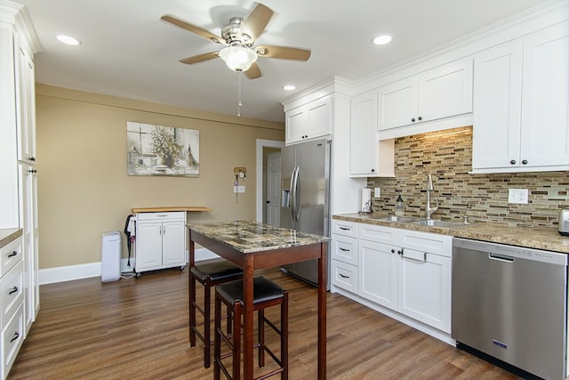 kitchen with light stone countertops, appliances with stainless steel finishes, dark hardwood / wood-style flooring, tasteful backsplash, and white cabinets