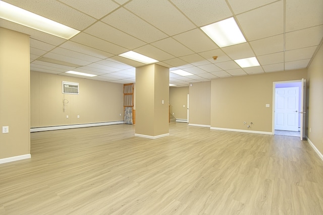 interior space featuring a paneled ceiling, a wall mounted AC, a baseboard radiator, and light hardwood / wood-style floors