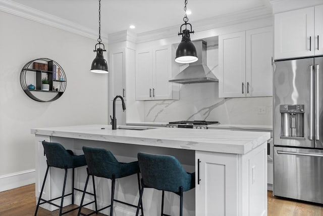 kitchen featuring wall chimney exhaust hood, a kitchen island with sink, and appliances with stainless steel finishes