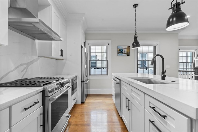 kitchen featuring white cabinets, stainless steel appliances, a wealth of natural light, and wall chimney range hood