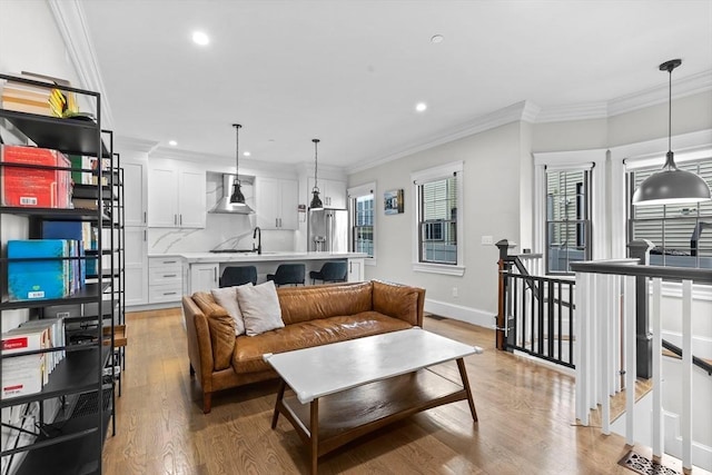 living room with crown molding, sink, and light hardwood / wood-style floors