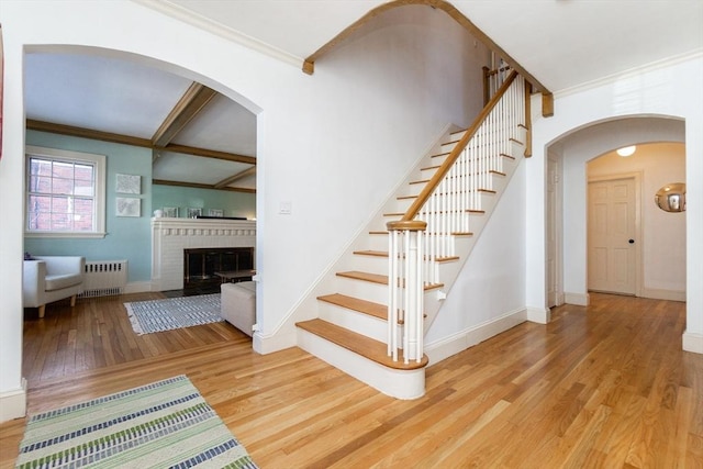 staircase with ornamental molding, radiator heating unit, and wood finished floors