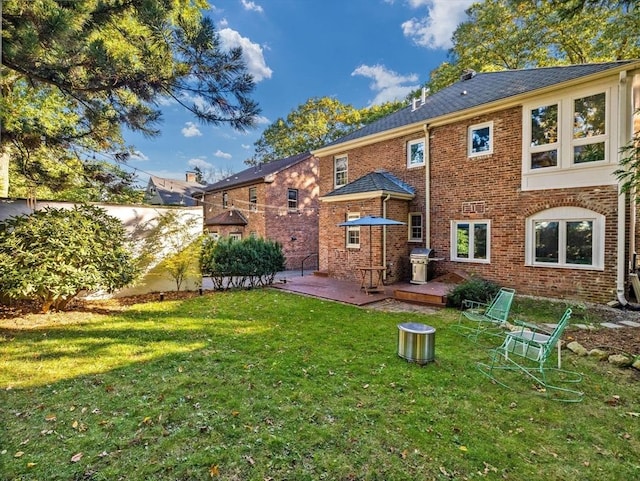 rear view of house with brick siding, a lawn, fence, and a patio