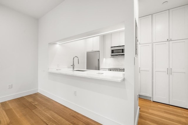 2 Clarendon St Unit 510, Boston, MA 02116 - kitchen featuring stainless steel appliances, a sink, light countertops, white cabinetry, and light wood finished floors