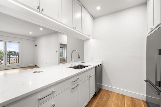 2 Clarendon St Unit 510, Boston, MA 02116 - kitchen with a sink, stainless steel appliances, light wood-type flooring, baseboards, and light stone counters