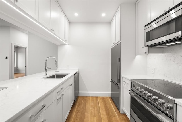 2 Clarendon St Unit 510, Boston, MA 02116 - kitchen featuring appliances with stainless steel finishes, a sink, light wood finished floors, white cabinetry, and recessed lighting