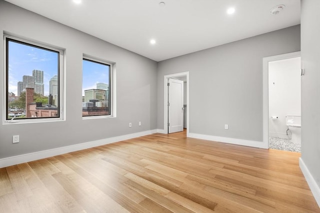 2 Clarendon St Unit 510, Boston, MA 02116 - unfurnished bedroom with light wood-style floors, baseboards, recessed lighting, connected bathroom, and a walk in closet