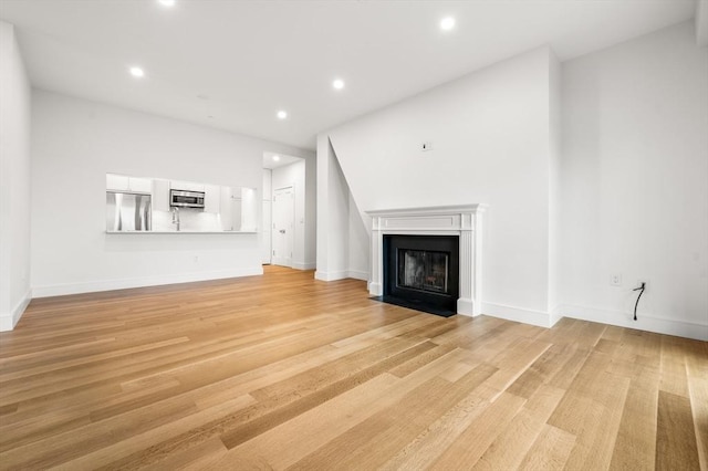 2 Clarendon St Unit 510, Boston, MA 02116 - unfurnished living room with a fireplace with flush hearth, recessed lighting, light wood-style floors, and baseboards